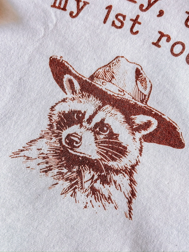 A natural t-shirt with a raccoon printed on it