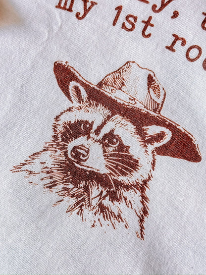 A natural t-shirt with a raccoon printed on it