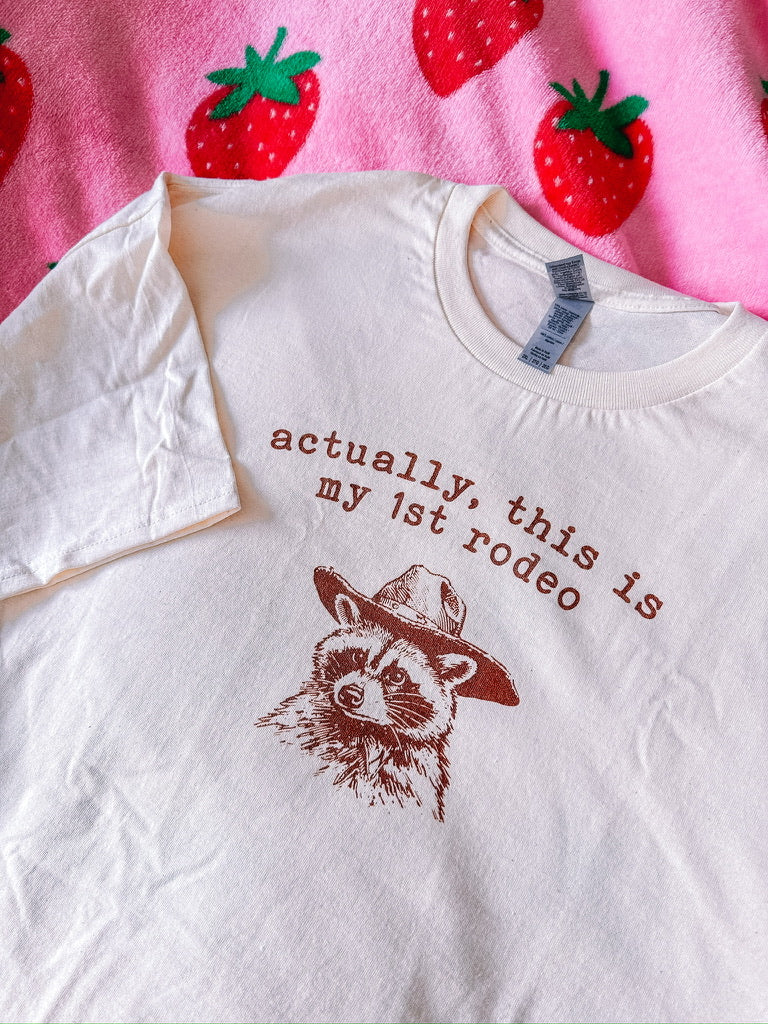 A natural t-shirt with a raccoon printed on it